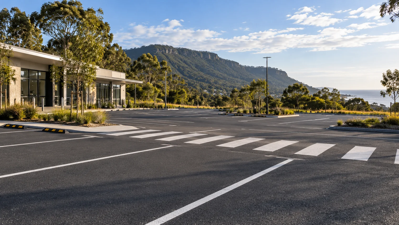 Illustrative commercial car park with fresh white markings and a green escarpment backdrop